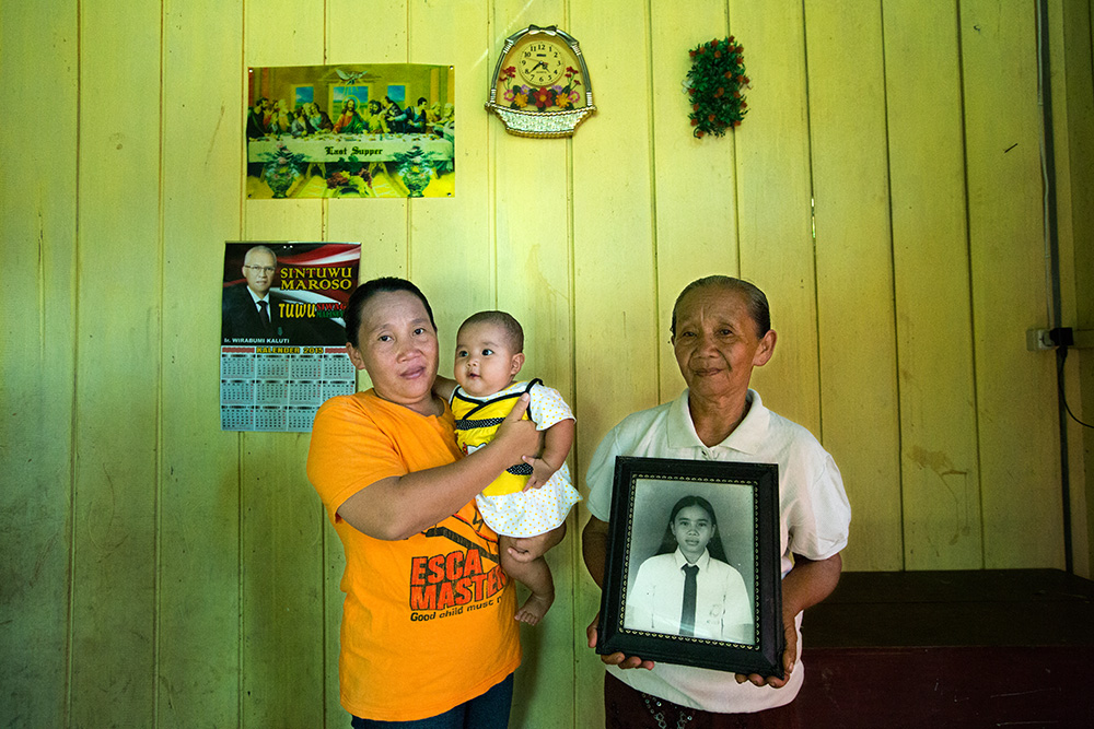 Nimuh Wandenda hold a portrait of her 15 years old daughter Theresia Morangki beheaded by Muslim radicals on her way to school. Theresia's older sister Yuyun hold her baby.
