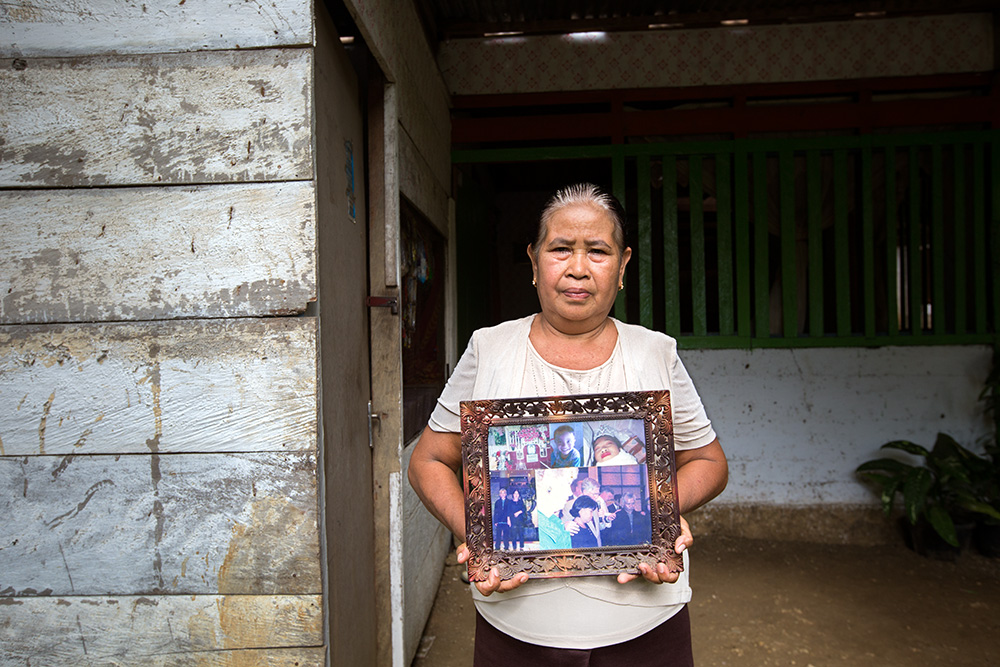 Hadirita Rongkombulu - a mother of beheaded 15 years old Yarni Sambue - with family photos including one of her murdered daughter lying in a coffin (up-right).