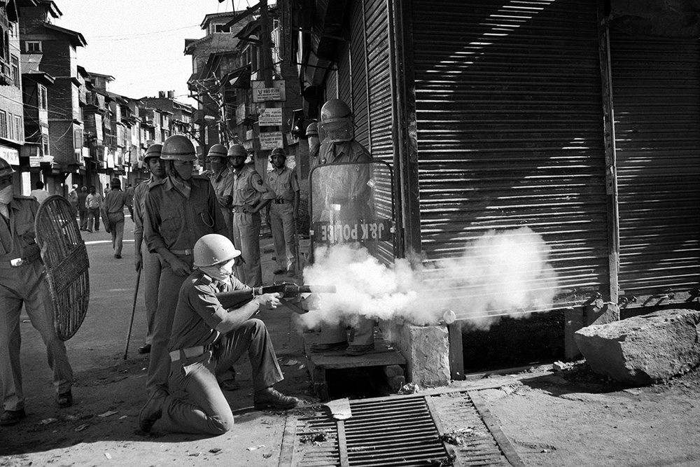Srinagar. Indian police fire a tear gas shell at local youths.