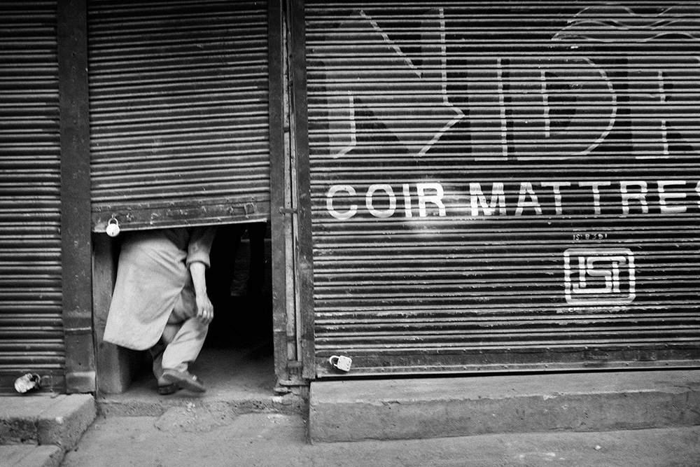 The strike against the violence of the police. One of the vendors hides in his own shop during the fights between local youths and Indian police.